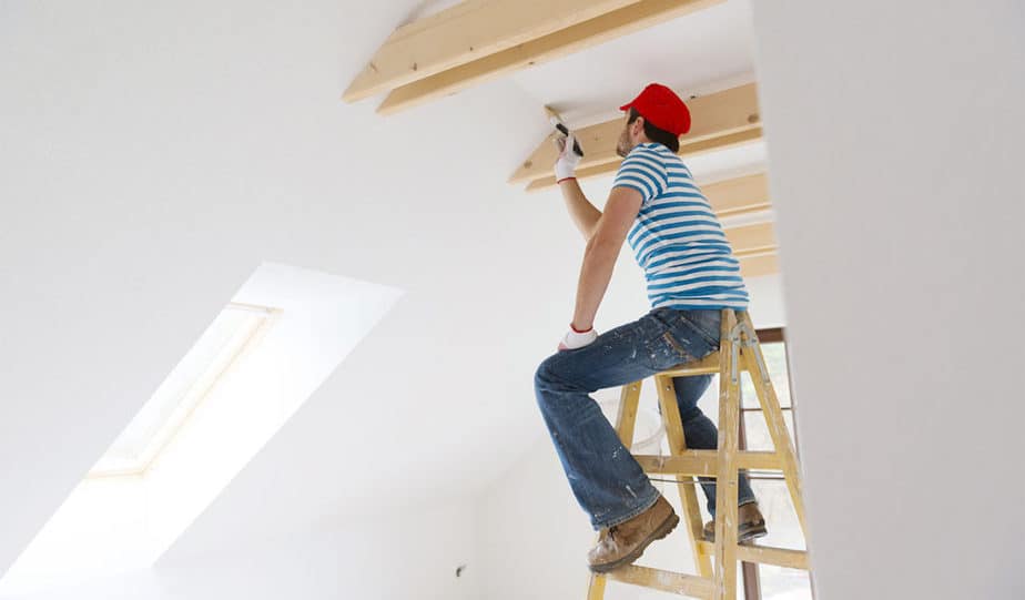 man painting the ceiling of a home